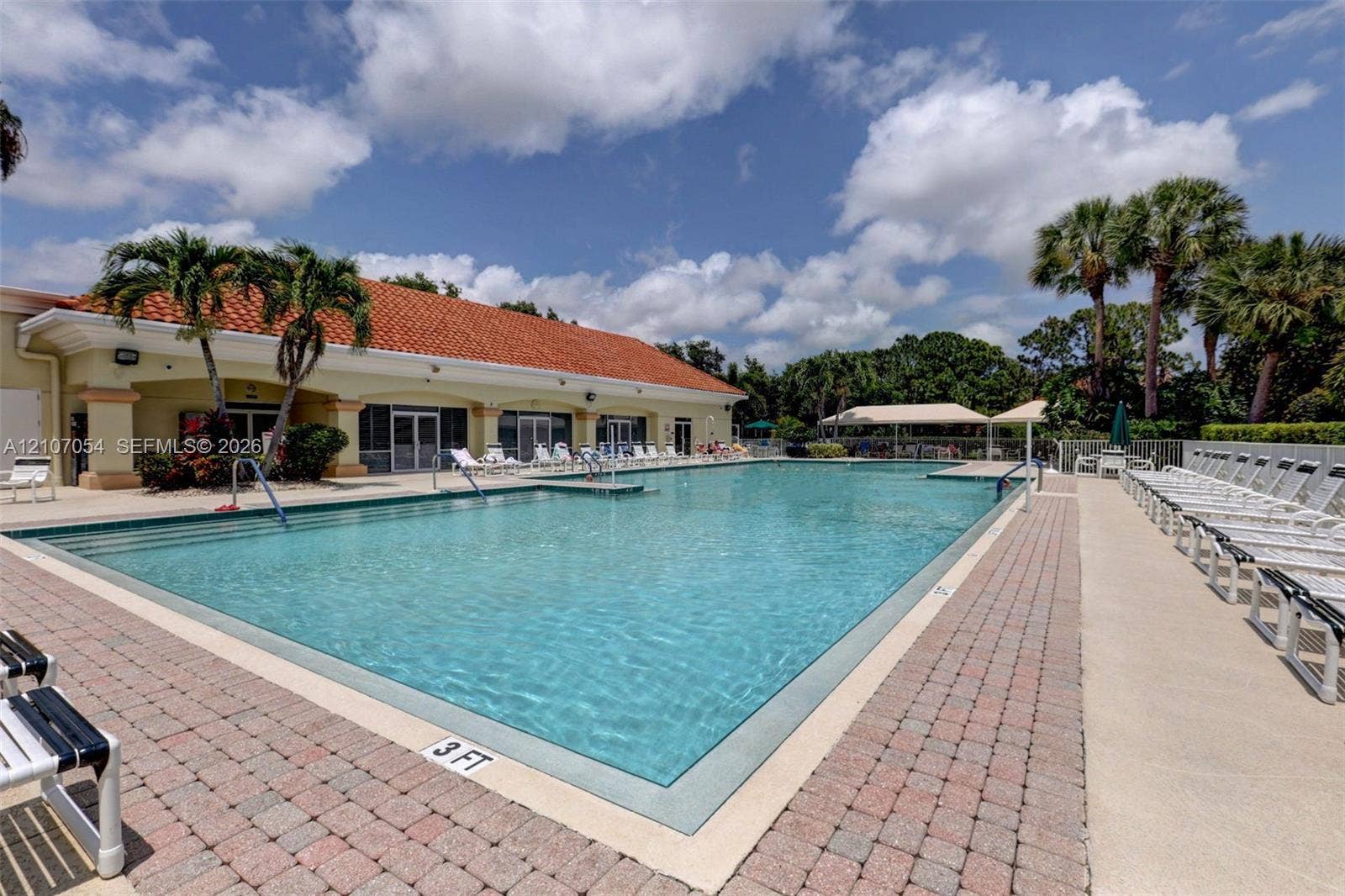 210 NW Zanzibar Place, Port St Lucie, FL 34986 Swimming pool with stepped entry, surrounding brick paver decking, and a terracotta tile roof structure