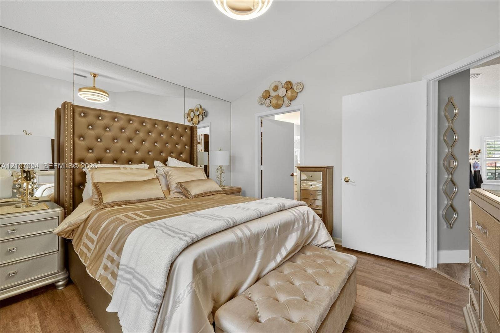210 NW Zanzibar Place, Port St Lucie, FL 34986 Vaulted ceilings featuring a circular flush-mount light fixture, full-wall mirrored accent, and laminate flooring