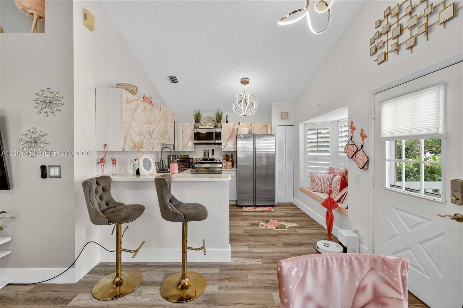 Kitchen featuring patterned cabinetry, stainless steel appliances, laminate flooring, vaulted ceilings, and a built-in window seat