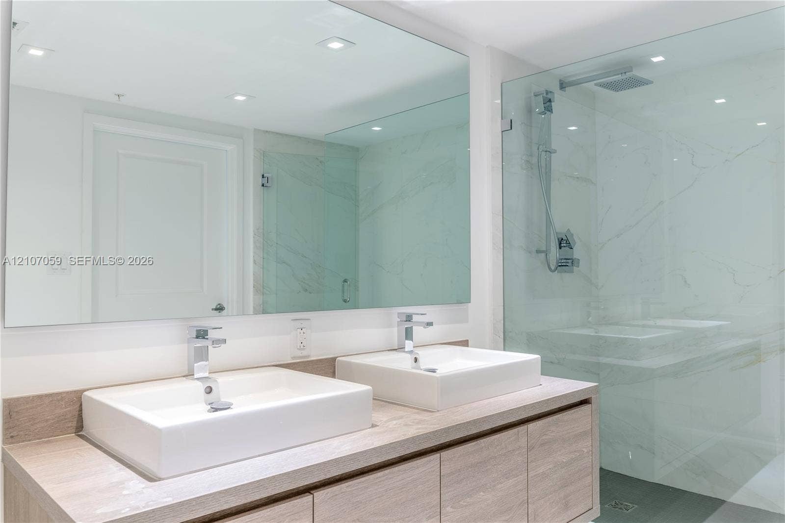 400 Sunny Isles Boulevard, #121, Sunny Isles Beach, FL 33160 Double vanity featuring wood-finish cabinetry, rectangular vessel sinks, polished chrome faucets, and a frameless glass-enclosed shower with large-format stone-tile surround