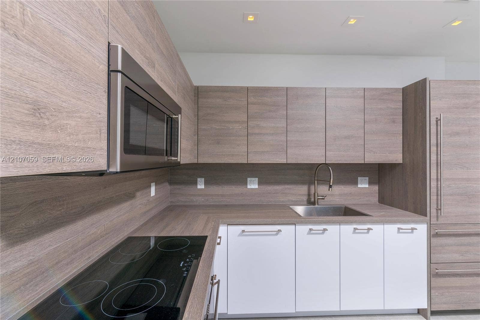 400 Sunny Isles Boulevard, #121, Sunny Isles Beach, FL 33160 Kitchen featuring wood-finish cabinetry, integrated stainless steel appliances, a flush-mount electric cooktop, quartz-finish countertops, and a stainless steel under-mount sink with a gooseneck faucet