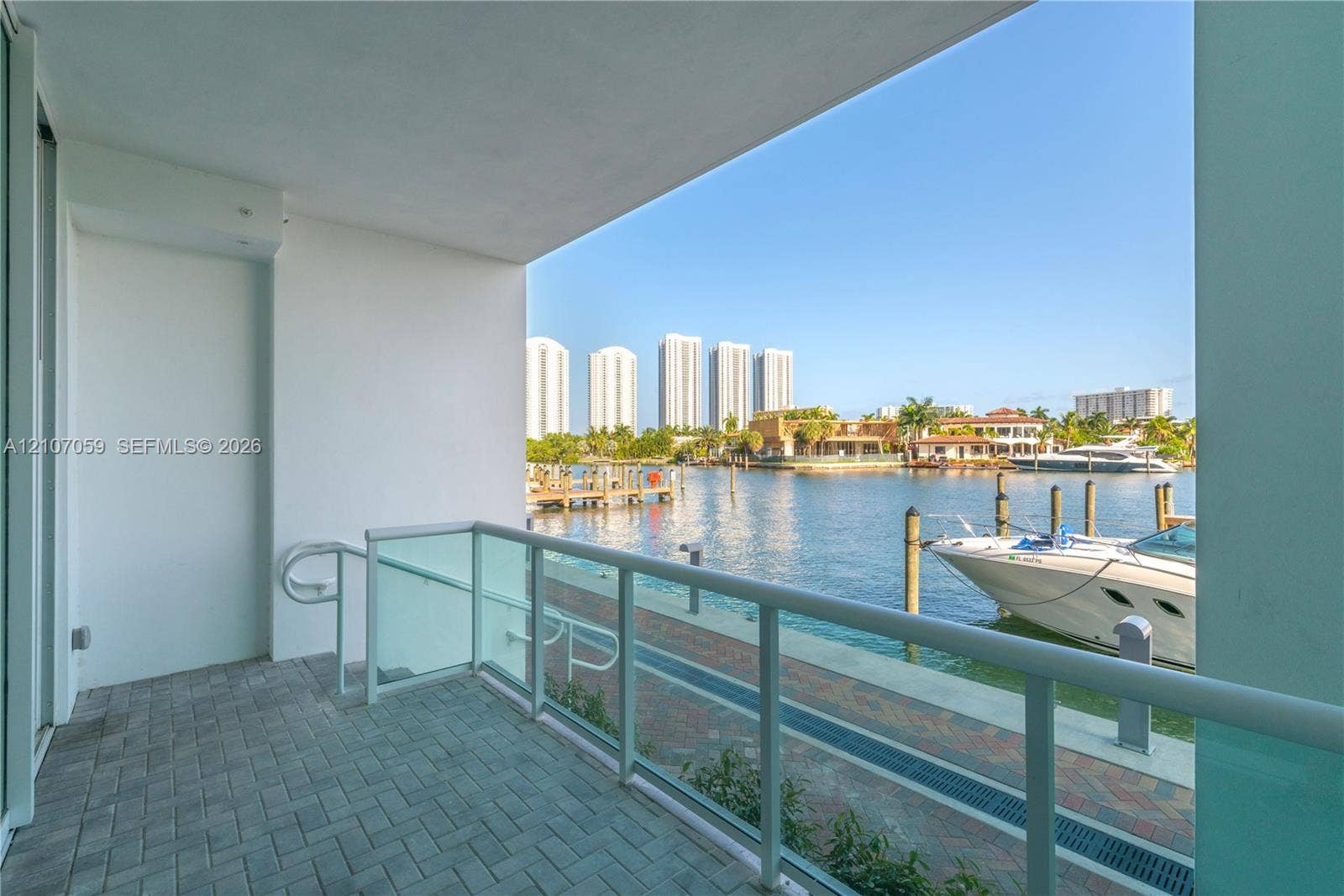 400 Sunny Isles Boulevard, #121, Sunny Isles Beach, FL 33160 Covered balcony with brick paver flooring, glass railing system, and direct waterfront access