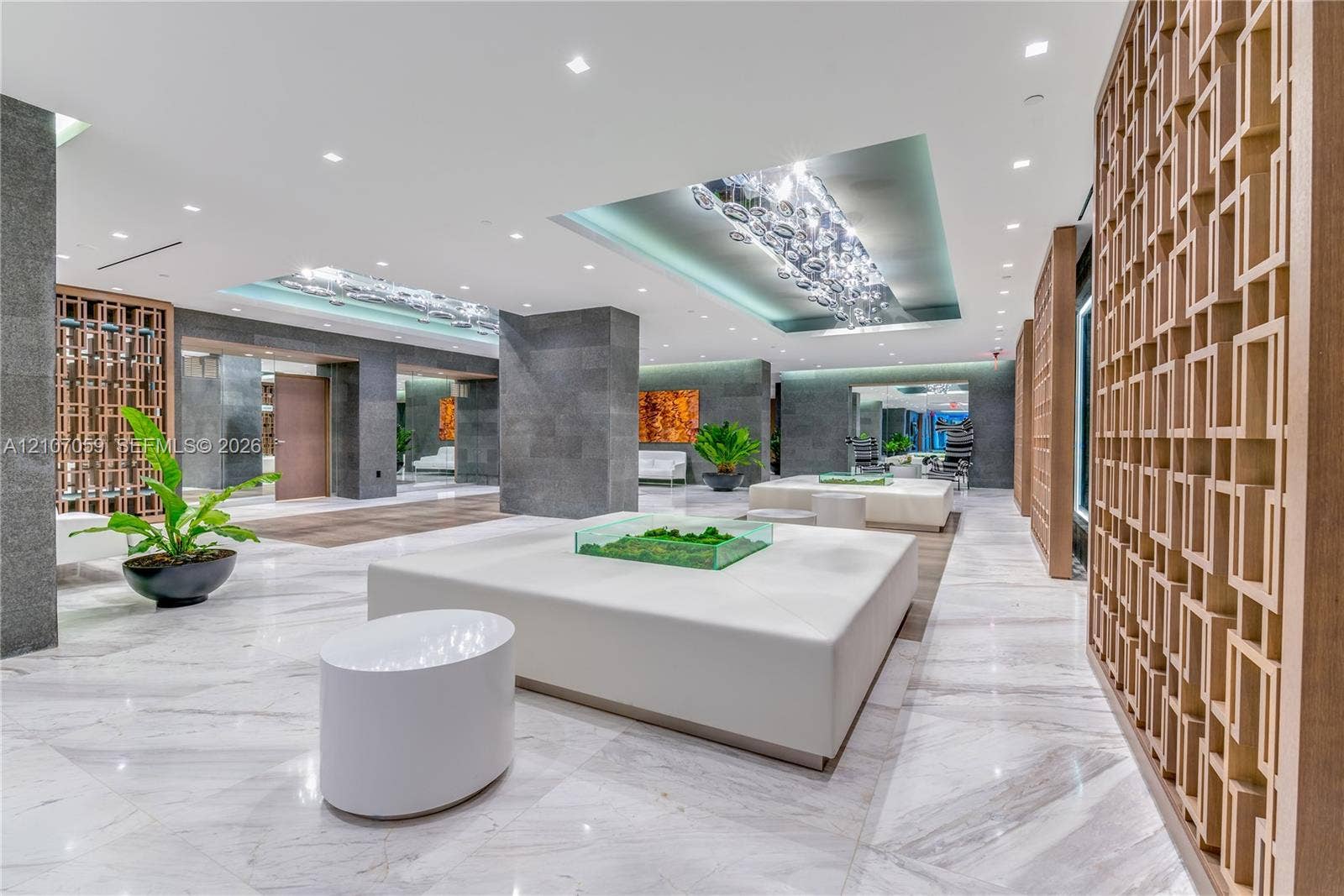 400 Sunny Isles Boulevard, #121, Sunny Isles Beach, FL 33160 Polished stone flooring, geometric wood-finish privacy screens, recessed tray ceilings with custom glass light fixtures, and stone-clad architectural columns