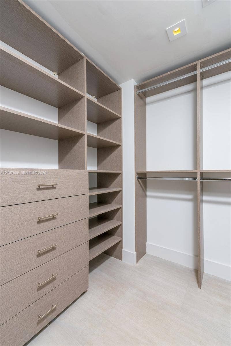 400 Sunny Isles Boulevard, #121, Sunny Isles Beach, FL 33160 Custom walk-in closet featuring floor-to-ceiling wooden cabinetry, built-in drawer units, adjustable shelving, and integrated metal clothing rods
