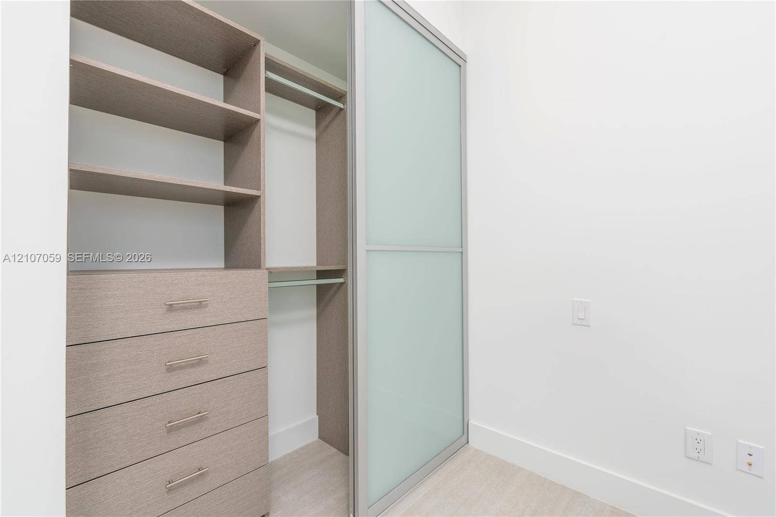 400 Sunny Isles Boulevard, #121, Sunny Isles Beach, FL 33160 Built-in closet organization system featuring wood-finish cabinetry, open shelving, integrated hanging rods, and frosted glass sliding panels