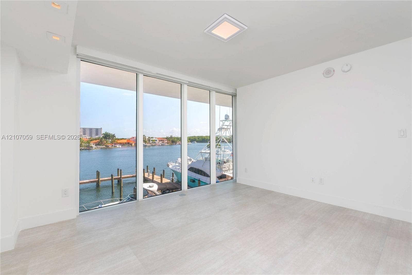 400 Sunny Isles Boulevard, #121, Sunny Isles Beach, FL 33160 Floor-to-ceiling windows featuring water frontage, wood-finish tile flooring, recessed lighting, and a square flush-mount ceiling fixture
