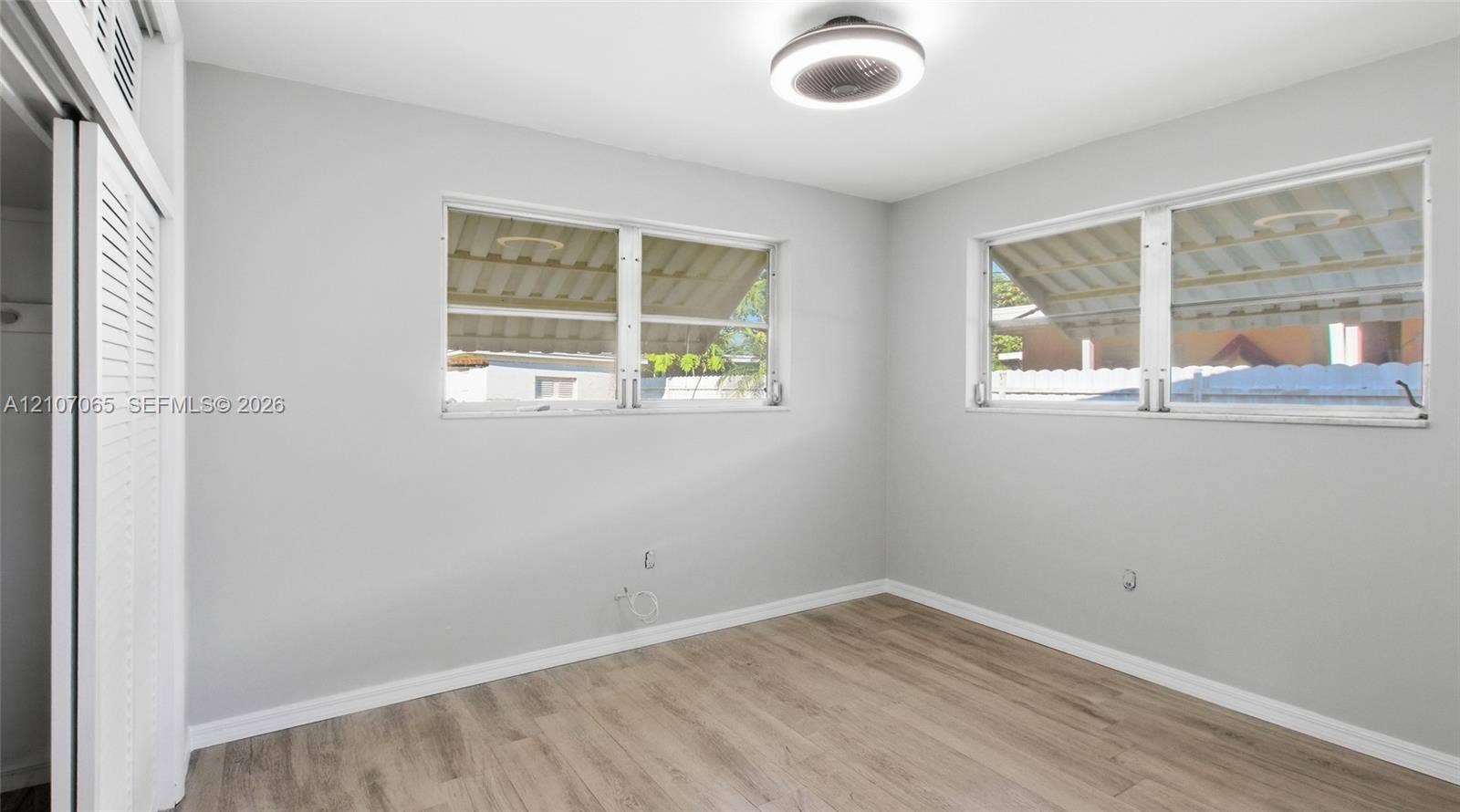 Neutral wall tones, wood-finish flooring, dual windows, and ceiling-mounted light fixture
