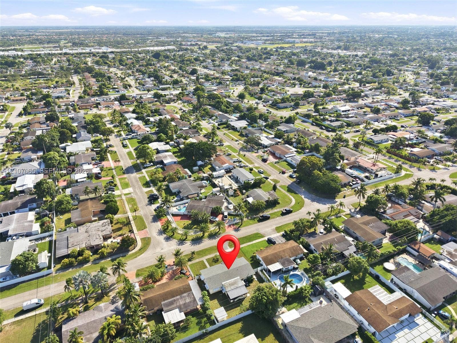 Aerial perspective of a corner lot residence featuring a shingled roof, paved driveway, and established perimeter landscaping