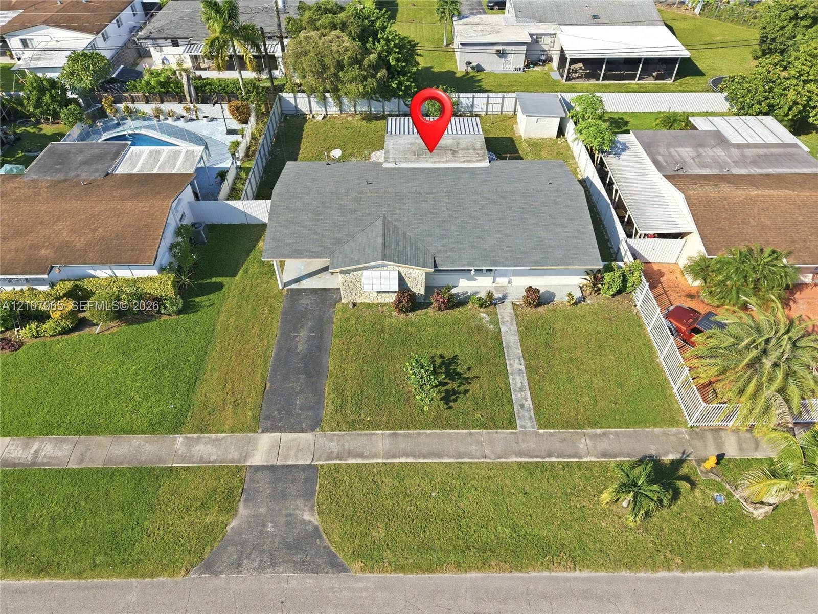 Single-story residence featuring a shingled roof, stone-veneer exterior facade, concrete driveway, and a fenced perimeter