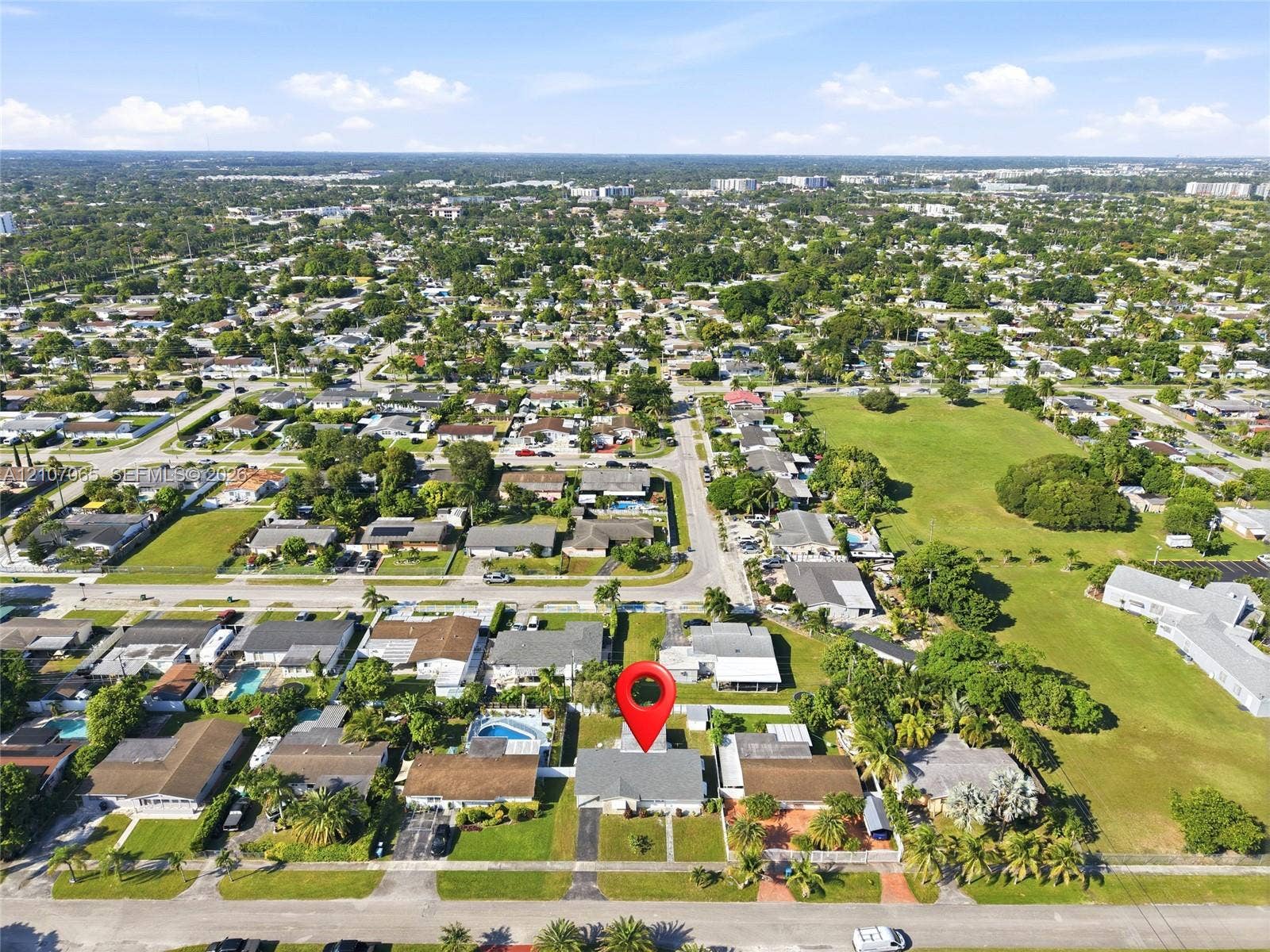 Aerial perspective of a residential property featuring a paved driveway, a structure with a pitched roof, and a fenced-in backyard