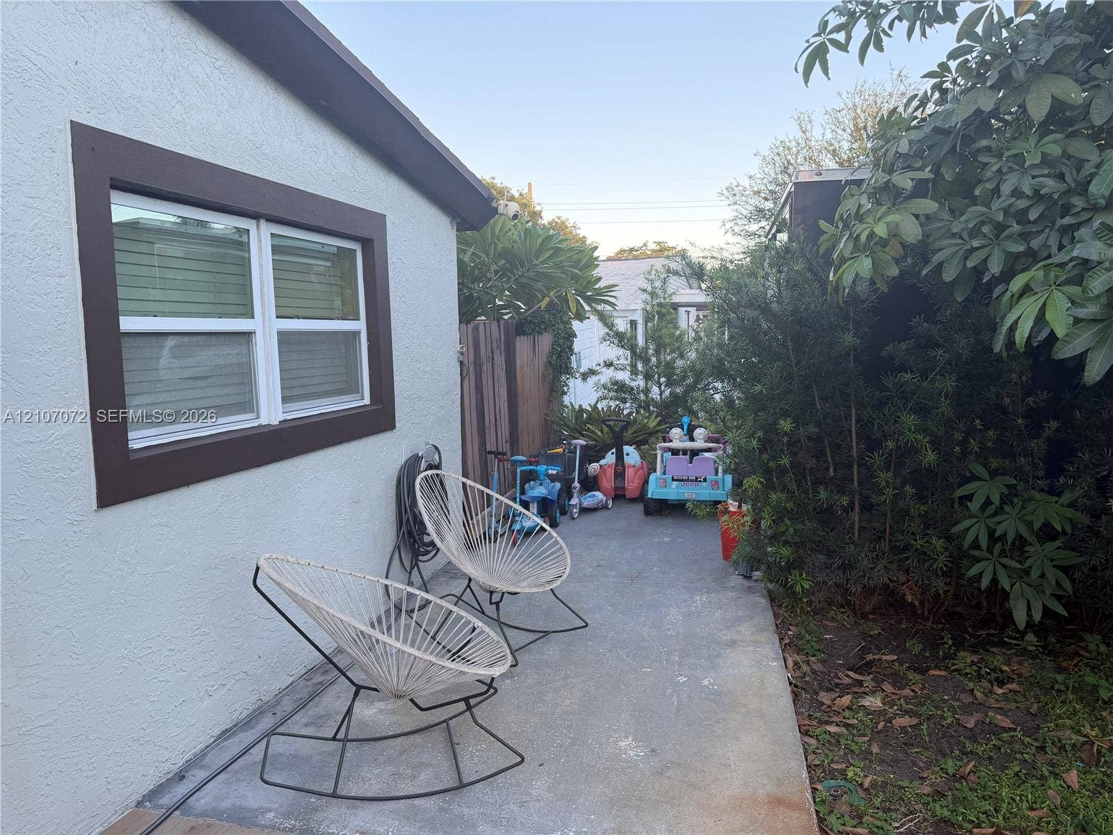 Stucco exterior siding, double-pane window with dark trim, and concrete patio area