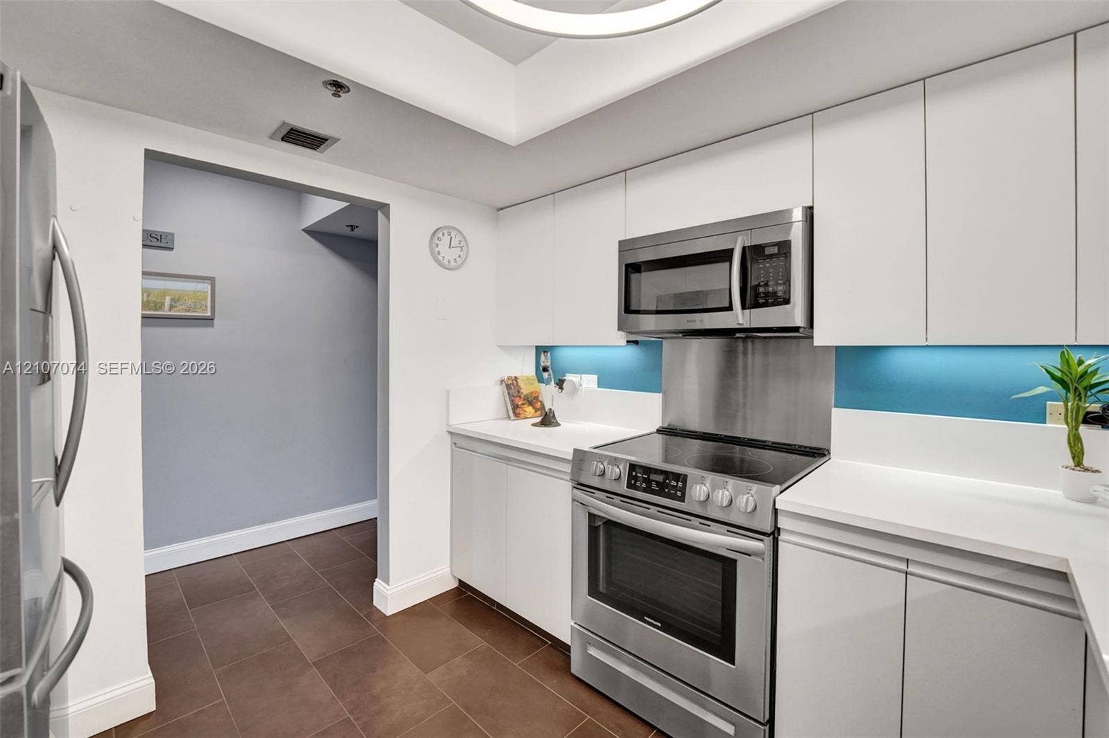 1201 S Ocean Drive, #218N, Hollywood, Hollywood, FL 33019 Kitchen featuring white flat-panel cabinetry, stainless steel appliance suite, solid-surface countertops, tile flooring, and recessed ceiling lighting