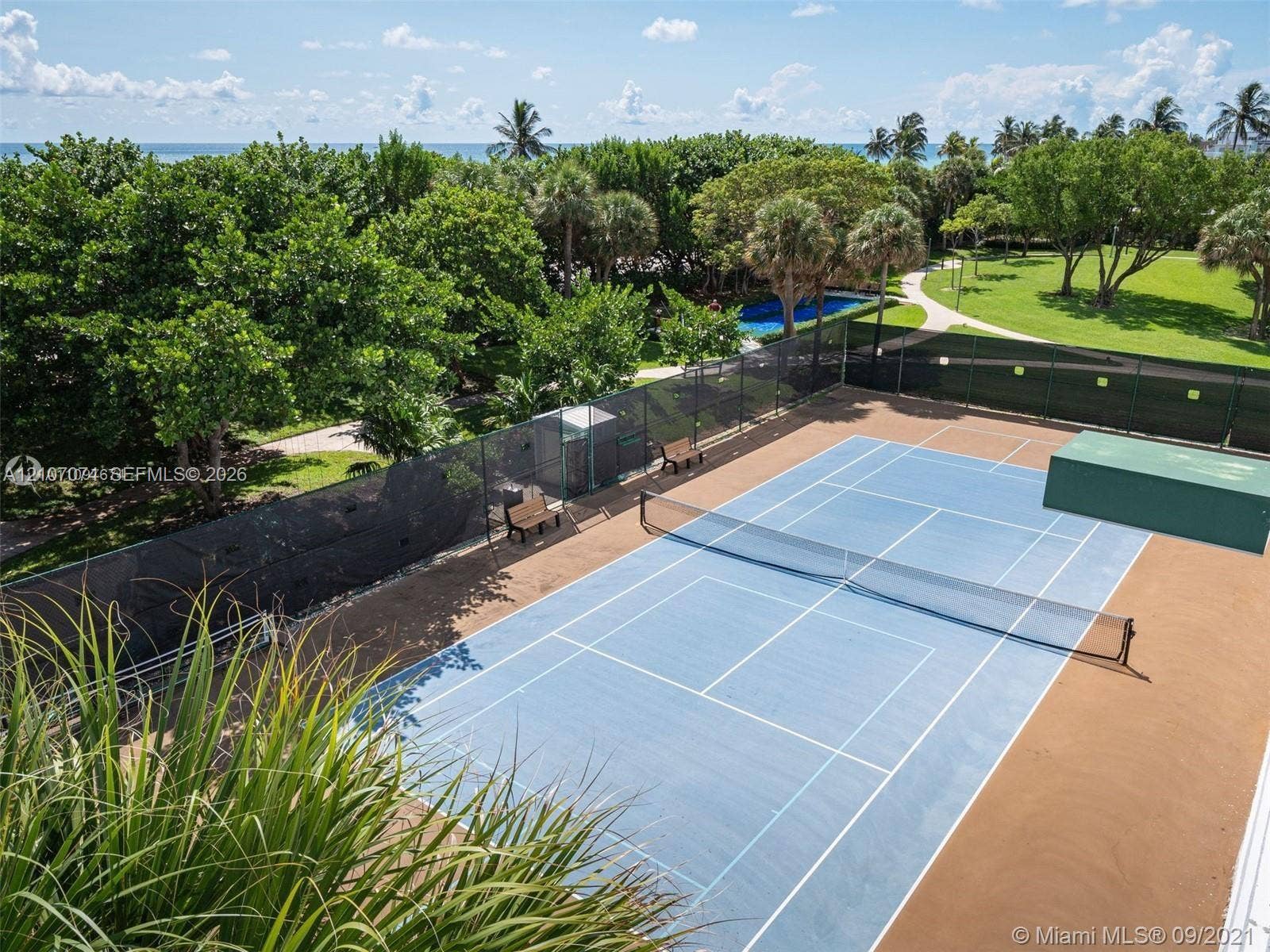 1201 S Ocean Drive, #218N, Hollywood, Hollywood, FL 33019 Tennis court with perimeter fencing, manicured landscaping, mature trees, and outdoor seating areas