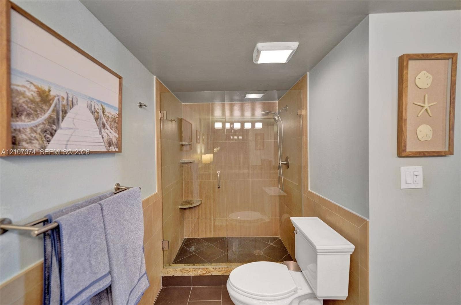 1201 S Ocean Drive, #218N, Hollywood, Hollywood, FL 33019 Walk-in glass enclosed shower with neutral wall tiling, stone floor tile, built-in corner shelf, and wall-mounted hand shower fixture