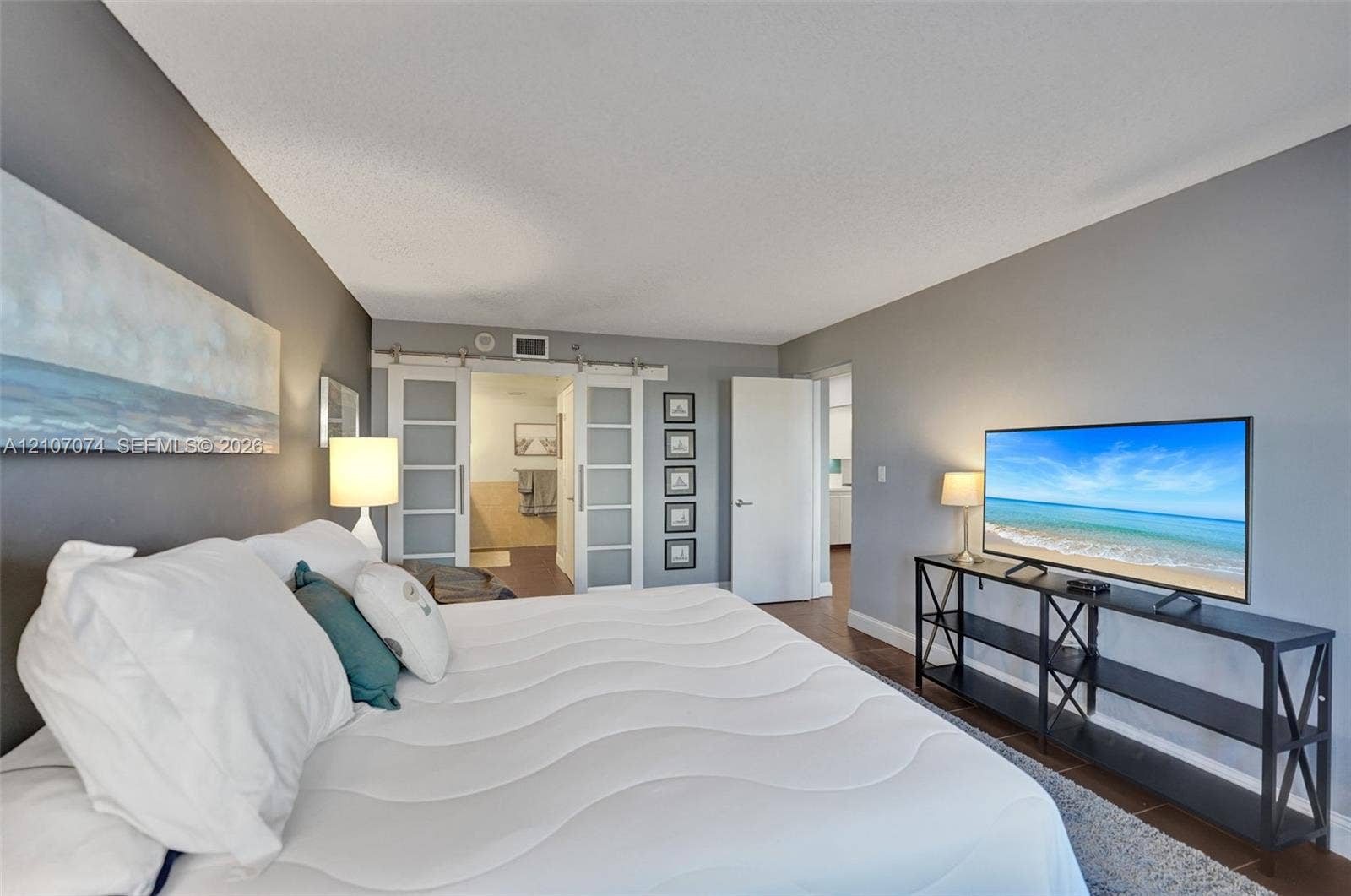 1201 S Ocean Drive, #218N, Hollywood, Hollywood, FL 33019 Dual sliding barn doors featuring frosted glass panels and metal hardware, complemented by wood-finish flooring