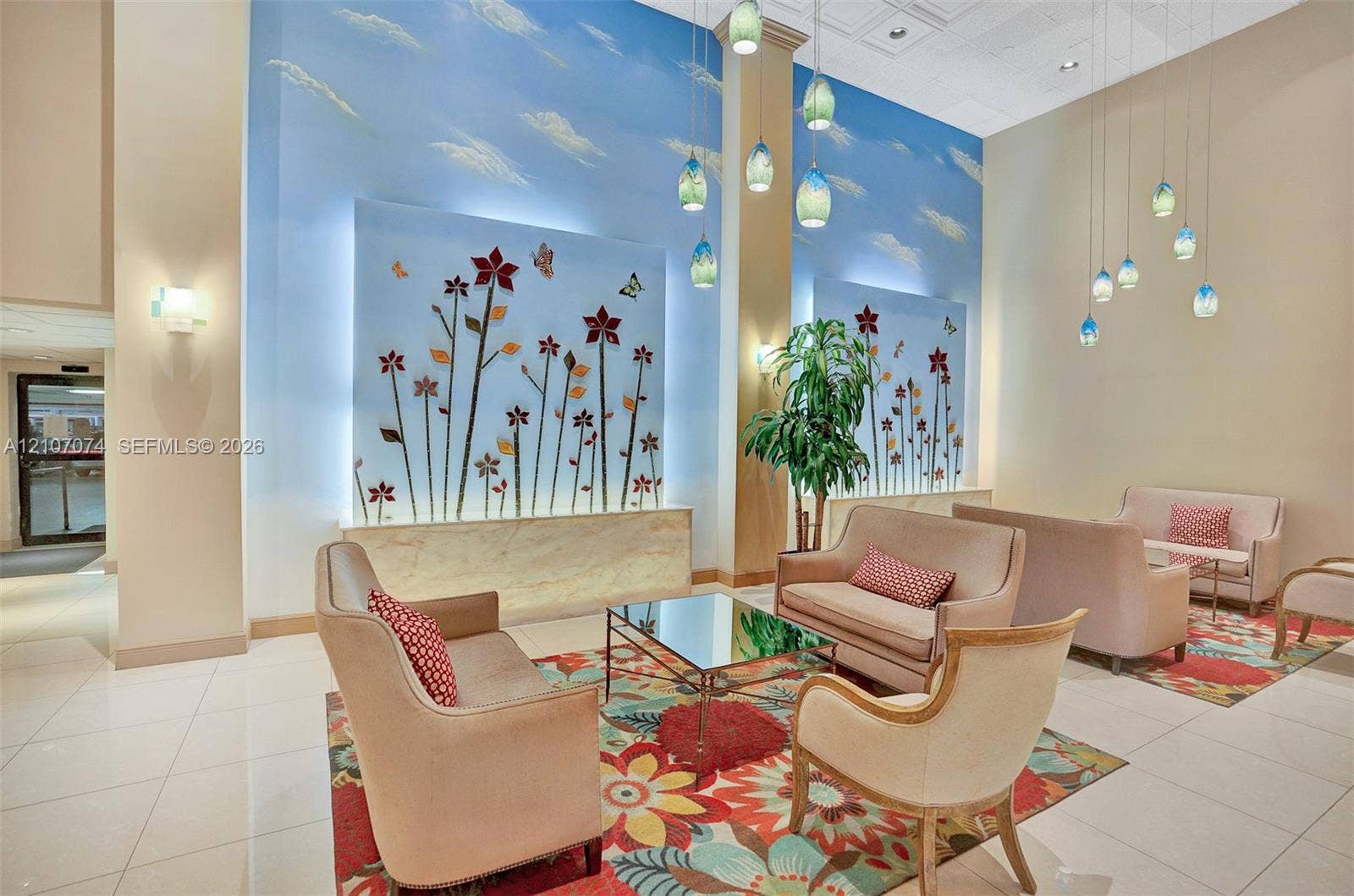 1201 S Ocean Drive, #218N, Hollywood, Hollywood, FL 33019 Double-height ceiling featuring recessed lighting and multiple tiered glass pendant fixtures, decorative wall-mounted floral relief murals with integrated backlighting, and polished tile flooring