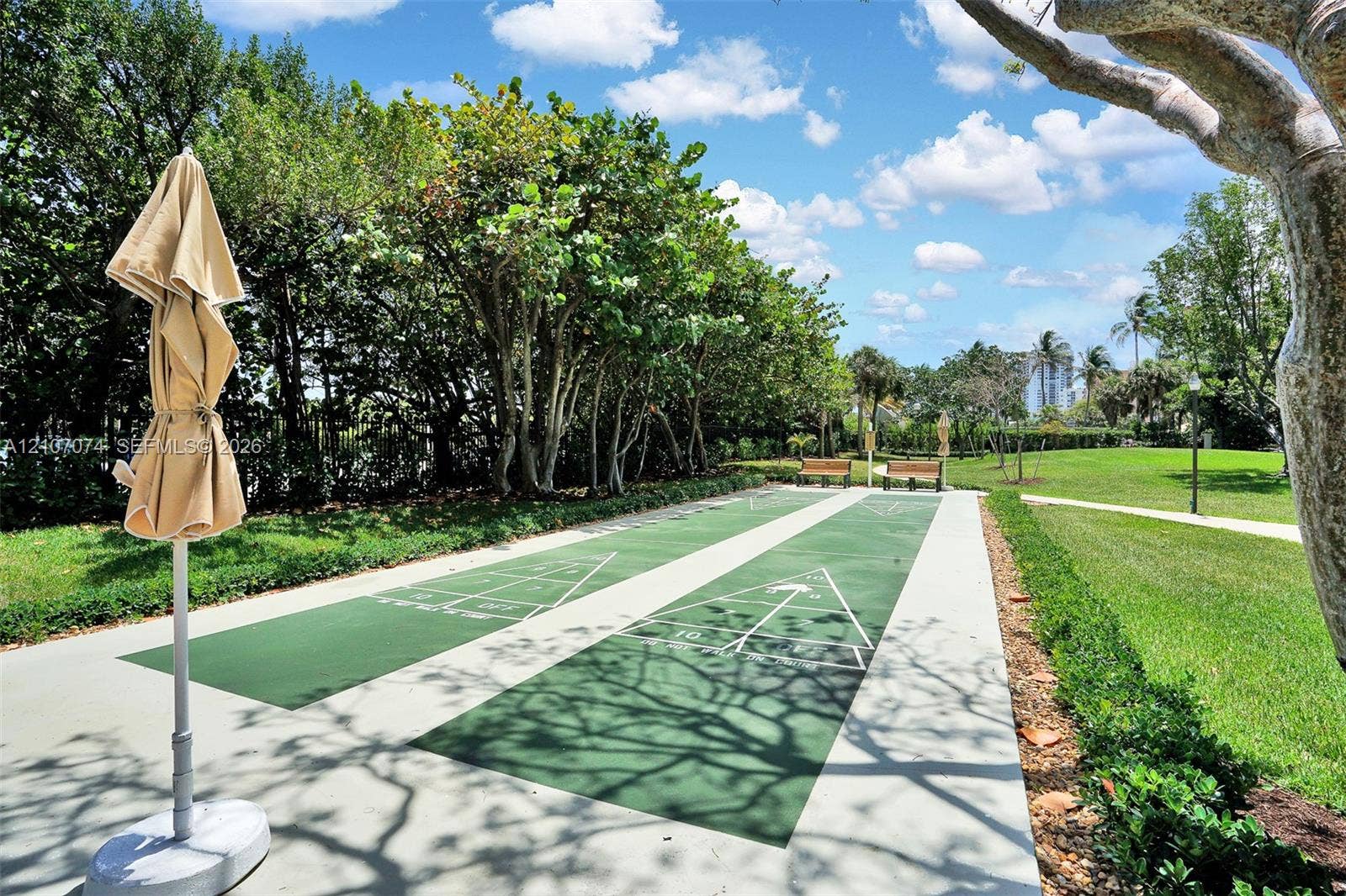 1201 S Ocean Drive, #218N, Hollywood, Hollywood, FL 33019 Dual shuffleboard court with painted green surfaces, concrete borders, landscaped perimeter, and mature shade trees