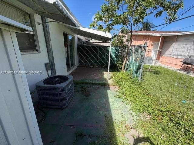 2450 Lincoln Street, #3, Hollywood, Hollywood, FL 33020 Concrete patio area featuring a fixed metal awning, exterior HVAC unit, and chain-link perimeter fencing