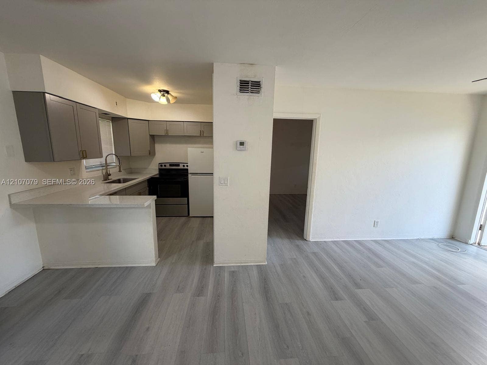 2450 Lincoln Street, #3, Hollywood, Hollywood, FL 33020 Kitchen featuring gray shaker-style cabinetry, solid-surface countertops, wood-finish flooring, and a stainless steel sink with gooseneck faucet
