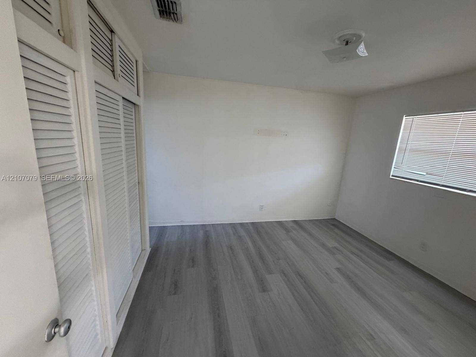 2450 Lincoln Street, #3, Hollywood, Hollywood, FL 33020 Room featuring wood-finish flooring, floor-to-ceiling louvered-style closets with overhead storage, and a window with horizontal blinds