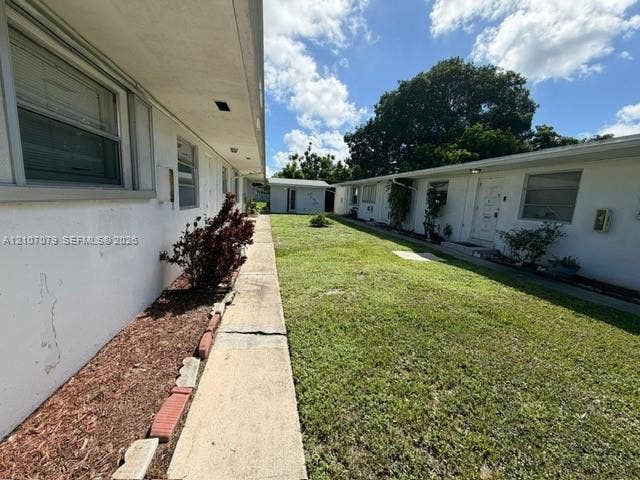 2450 Lincoln Street, #3, Hollywood, Hollywood, FL 33020 Exterior courtyard featuring concrete walkways, landscaped lawn, and white stucco building facades
