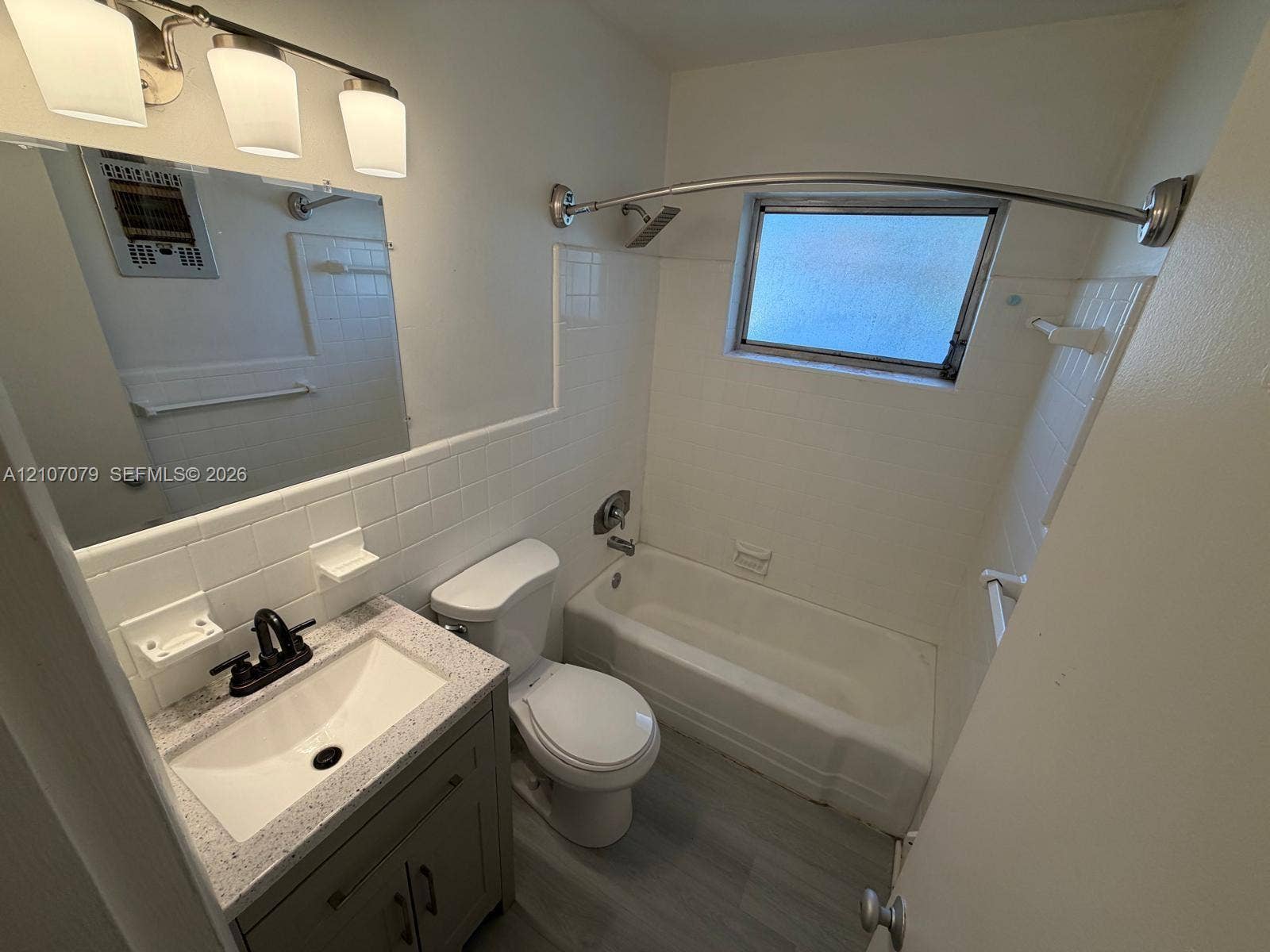 2450 Lincoln Street, #3, Hollywood, Hollywood, FL 33020 Bathroom featuring a vanity with a rectangular sink and stone-finish countertop, matte black faucet, wall-mounted light fixture, and a shower-tub combination with white tile surround