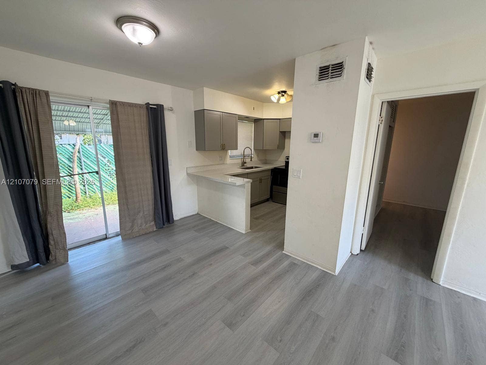 2450 Lincoln Street, #3, Hollywood, Hollywood, FL 33020 Kitchen area featuring wood-finish flooring, a breakfast bar with solid-surface countertops, grey cabinetry, and a sliding glass door