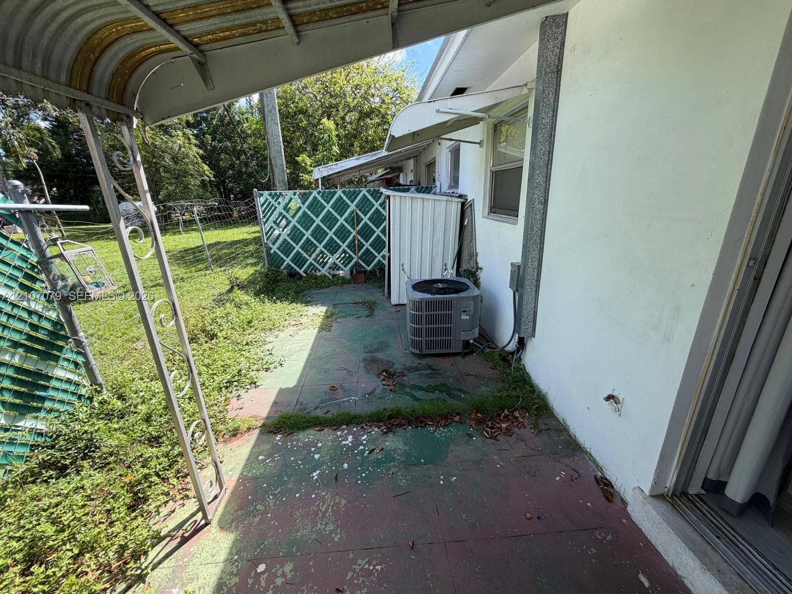 2450 Lincoln Street, #3, Hollywood, Hollywood, FL 33020 Covered concrete patio featuring metal structural supports, lattice fencing, and exterior climate control unit