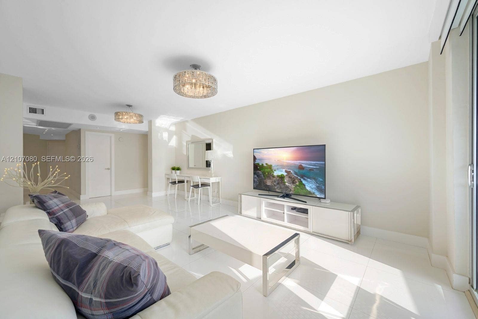 Open-concept living space featuring high-gloss tile flooring, dual contemporary drum-style pendant light fixtures, and sliding glass doors