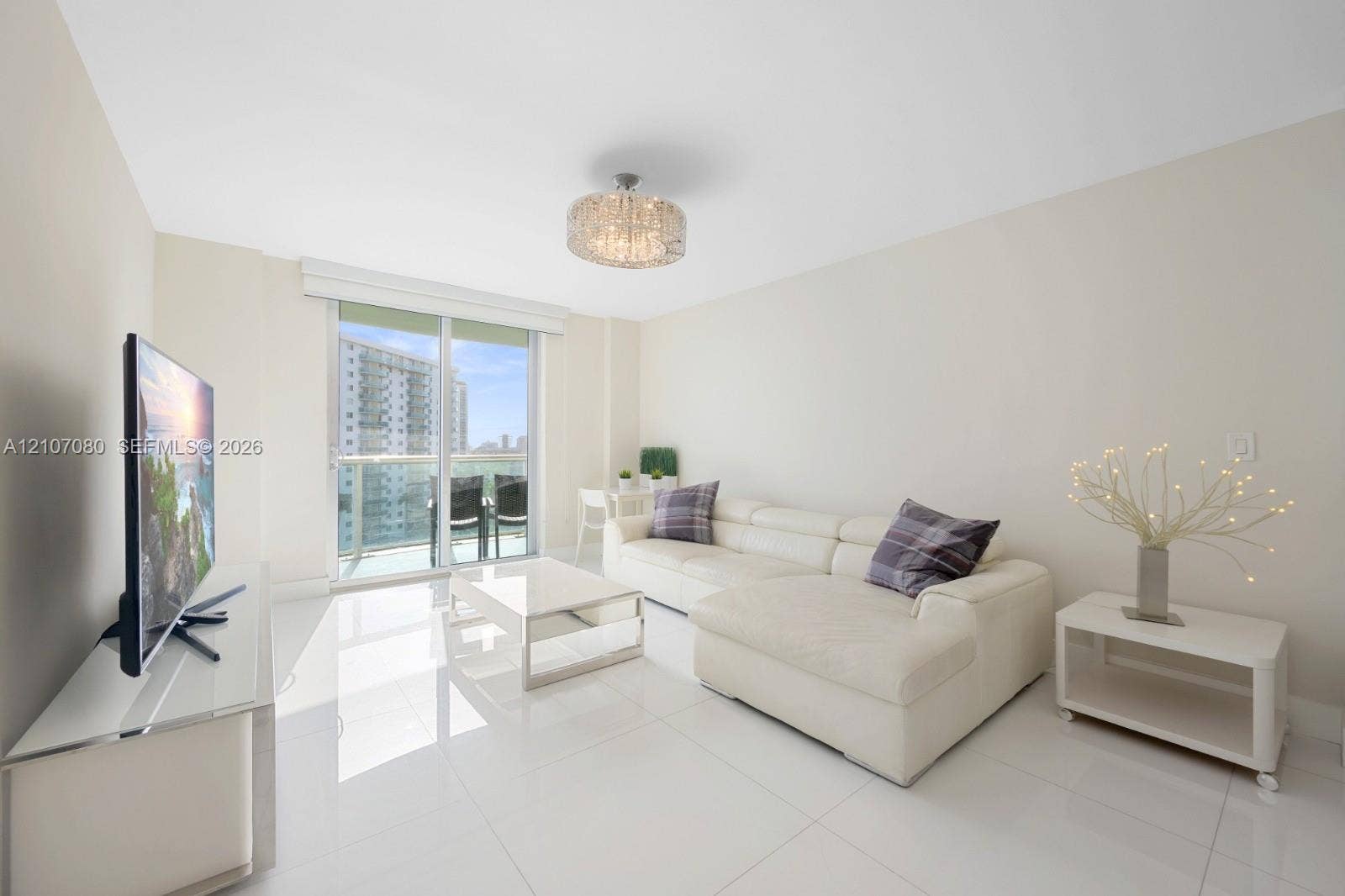 Large-format polished tile flooring, floor-to-ceiling glass sliding doors, private balcony, and decorative drum-style ceiling light fixture