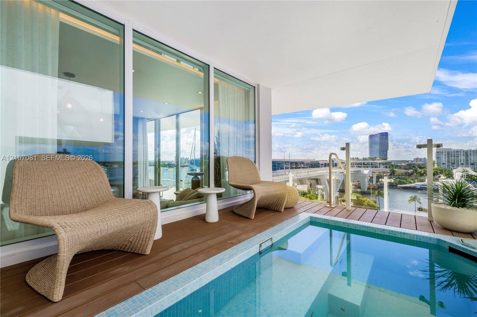 Covered balcony featuring wood-finish decking, a built-in plunge pool with tiled lining, floor-to-ceiling glass panel walls, and a glass-paneled railing