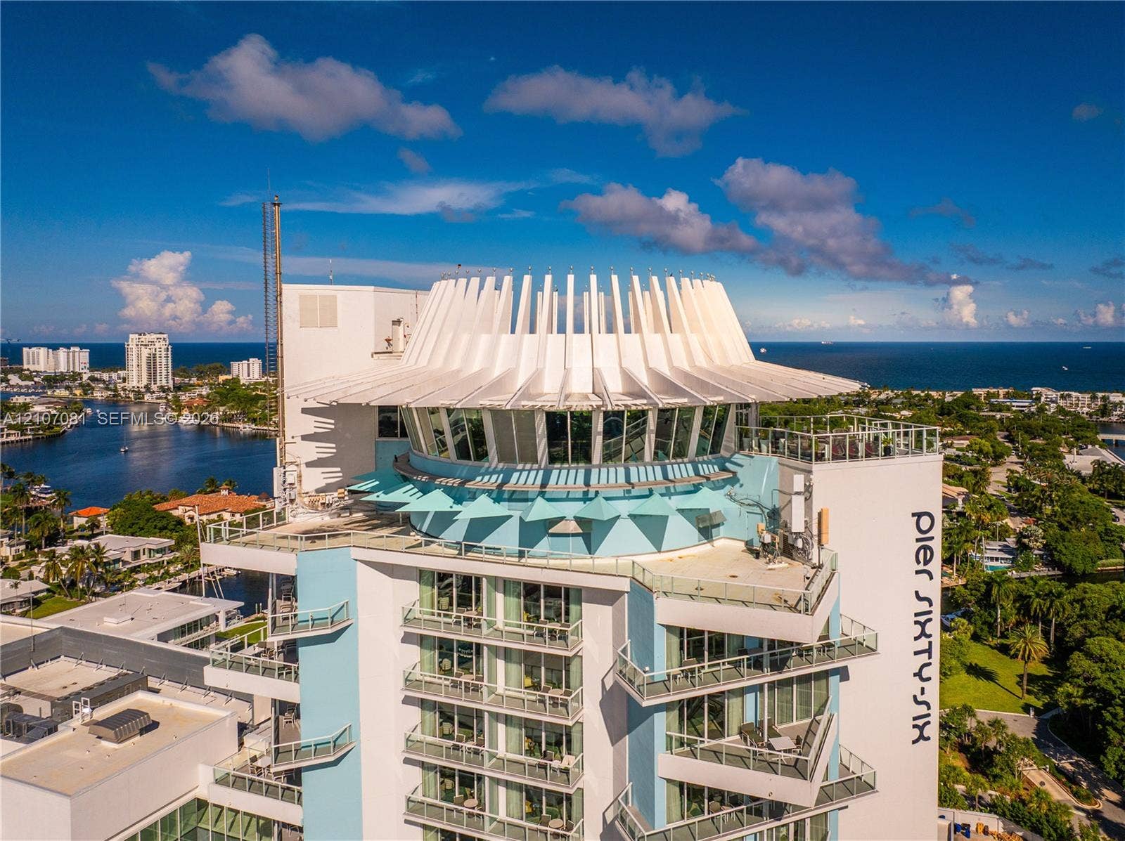High-rise building featuring a distinctively sculpted crown, expansive floor-to-ceiling glass windows, tiered private balconies, and a reinforced concrete exterior