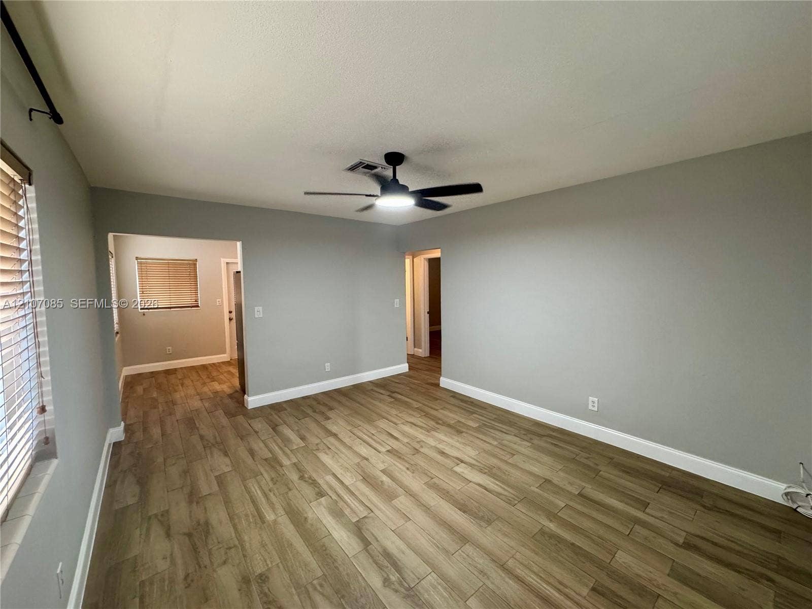 2641 SW 13th Avenue, #1, Fort Lauderdale, Fort Lauderdale, FL 33315 Neutral-toned interior space featuring wood-finish flooring, a multi-blade ceiling fan with integrated lighting, and horizontal window blinds
