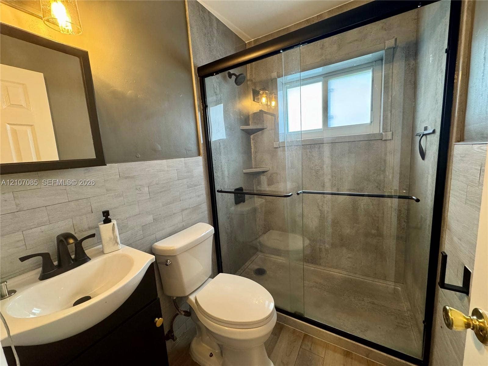 2641 SW 13th Avenue, #1, Fort Lauderdale, Fort Lauderdale, FL 33315 Bathroom featuring a walk-in shower with sliding glass doors, matte black fixtures, textured wall tile, and a vessel sink with a dark-finish vanity