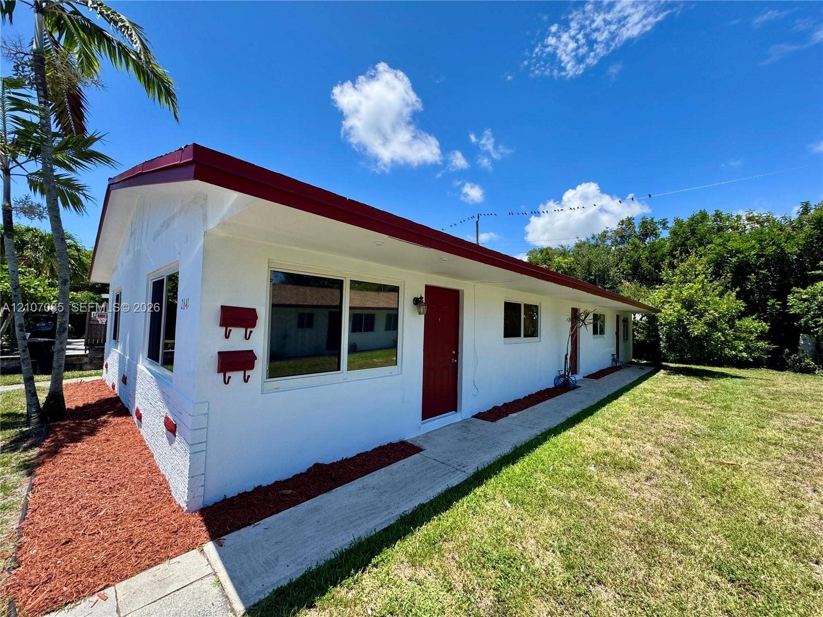 2641 SW 13th Avenue, #1, Fort Lauderdale, Fort Lauderdale, FL 33315 Single-story exterior featuring white stucco siding, a low-pitched roof with red eaves, a concrete walkway, and red entry doors