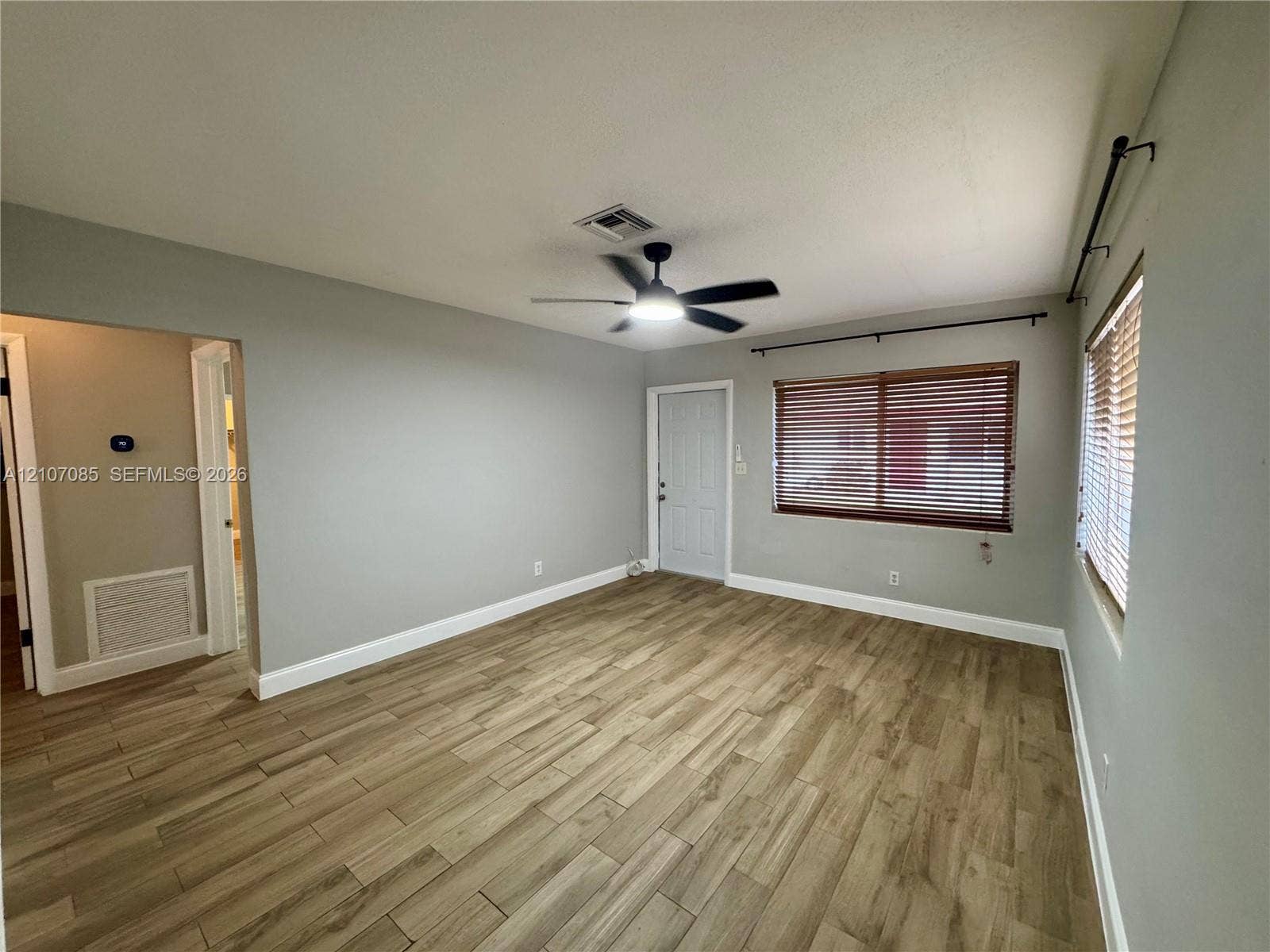 2641 SW 13th Avenue, #1, Fort Lauderdale, Fort Lauderdale, FL 33315 Neutral-toned interior space featuring wood-finish flooring, a multi-blade ceiling fan with integrated lighting, and windows outfitted with horizontal blinds