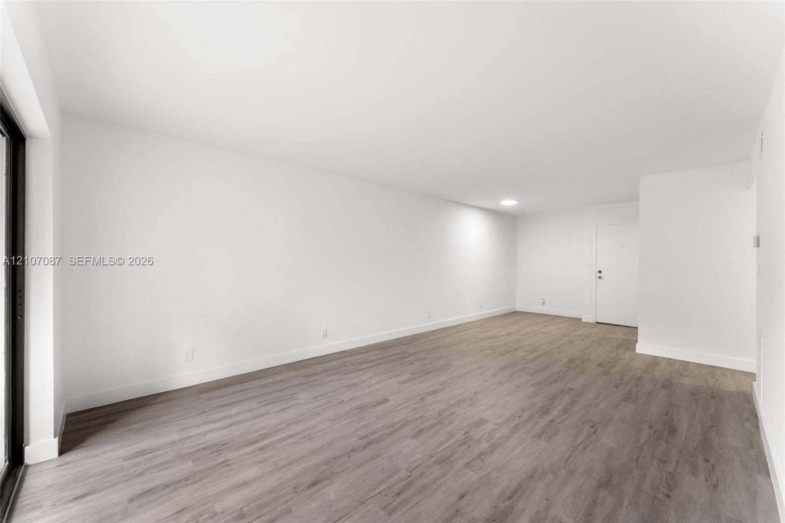 Open-concept room featuring neutral wall finishes, wood-finish flooring, recessed lighting, and a sliding glass door