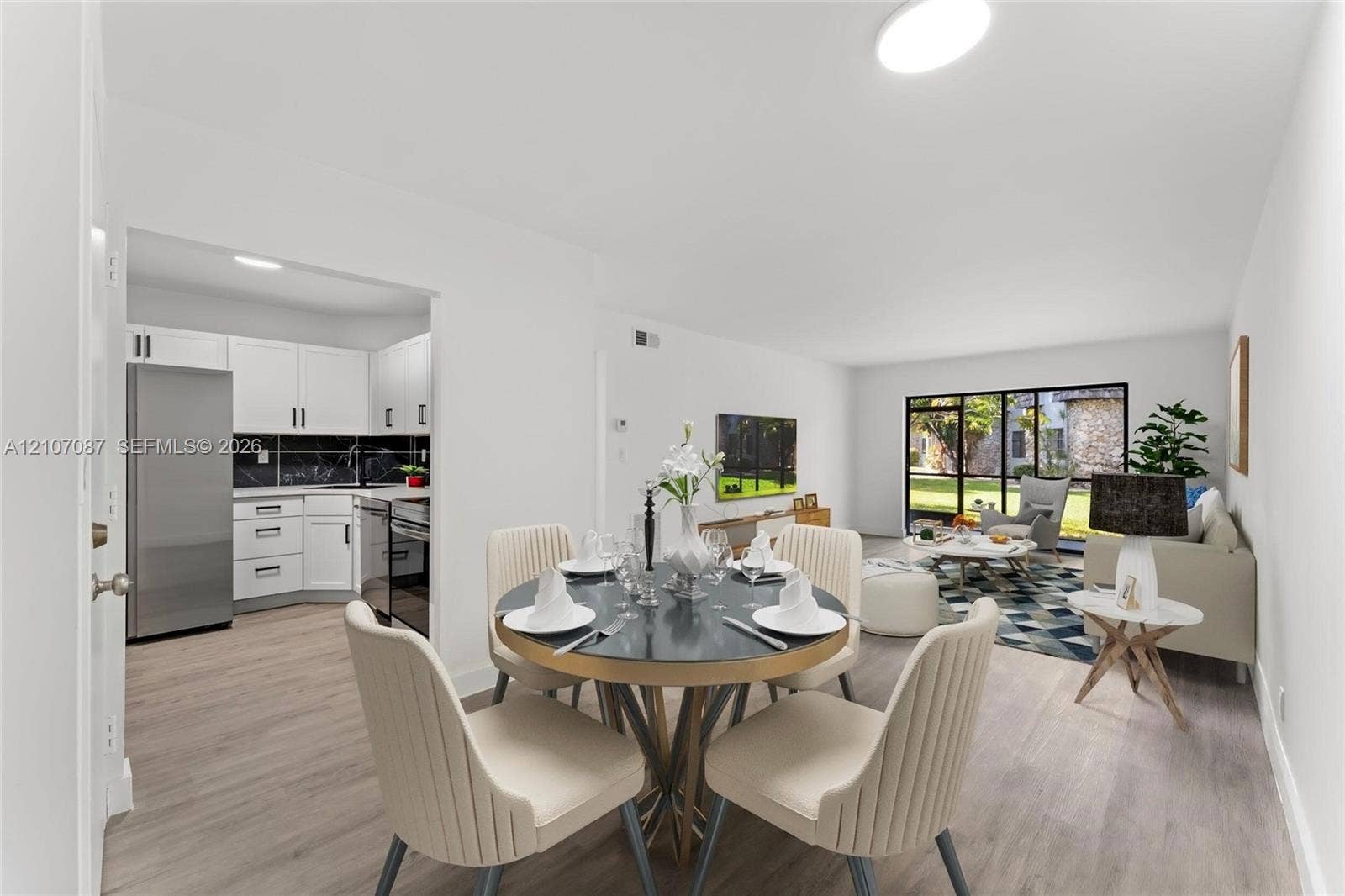 Interior space featuring wood-finish flooring, white cabinetry, dark stone-patterned backsplash, and expansive floor-to-ceiling windows