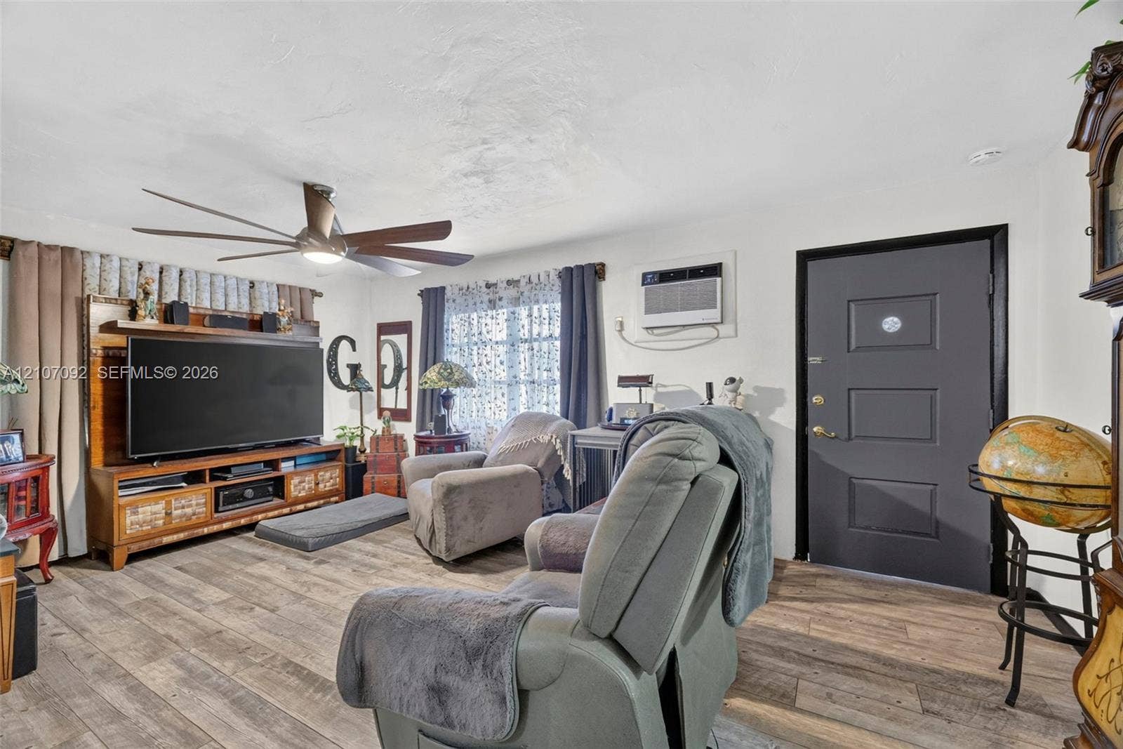 2864 NE 12th Terrace, Pompano Beach, FL 33064 Living area featuring wood-finish flooring, a multi-blade ceiling fan, and a dark-toned paneled entry door
