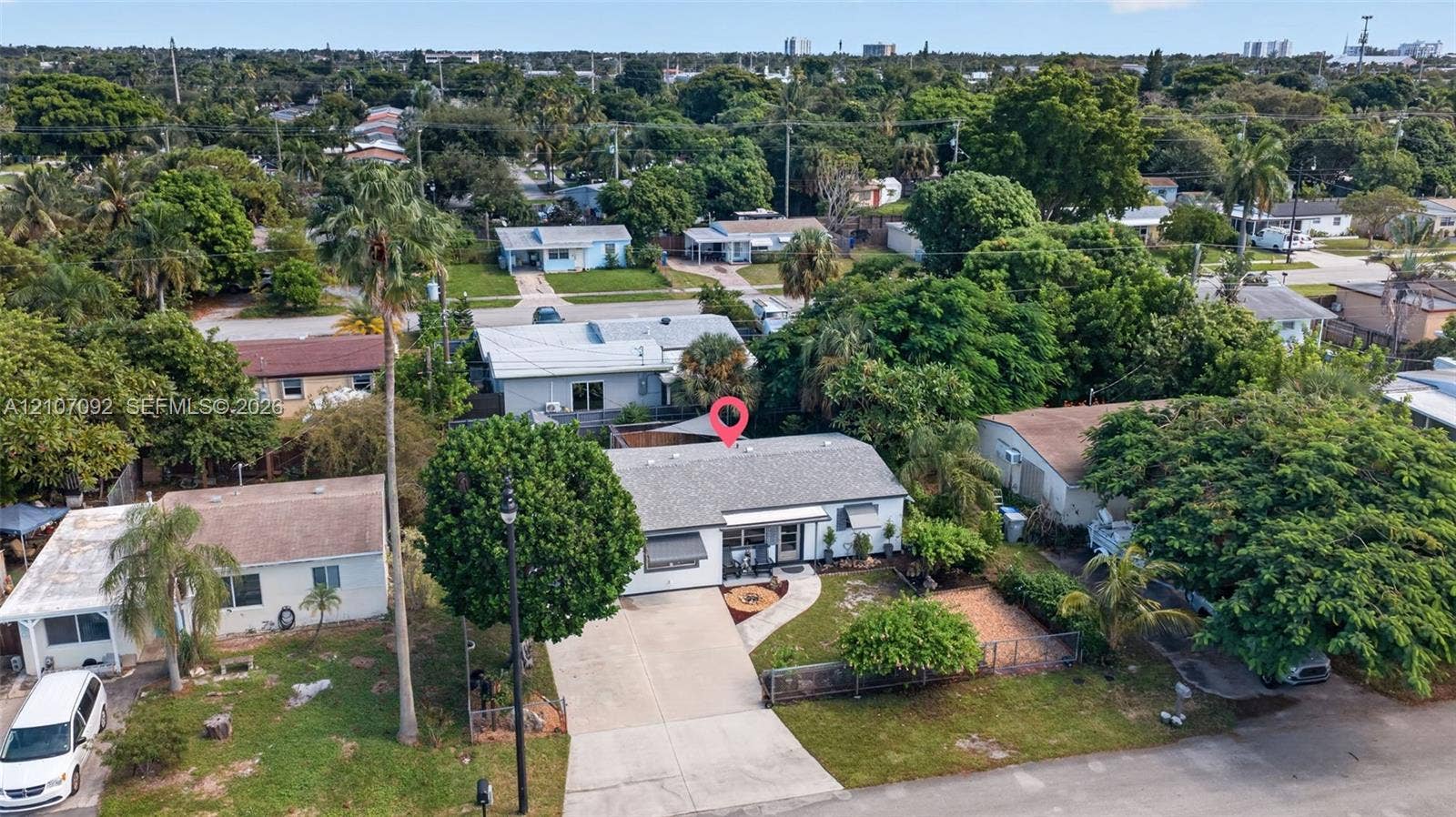 2864 NE 12th Terrace, Pompano Beach, FL 33064 Single-story residence featuring a shingled roof, light-toned exterior siding, concrete driveway, and established landscaping