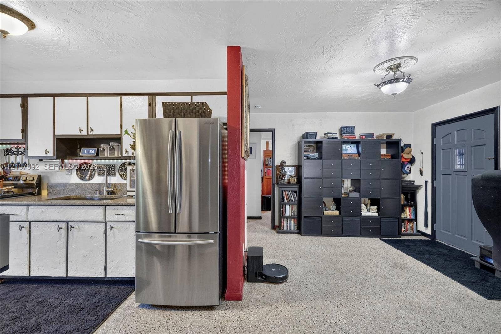 2864 NE 12th Terrace, Pompano Beach, FL 33064 Kitchen featuring white cabinetry, solid surface countertops, and a stainless steel French-door refrigerator, complemented by ceiling-mounted light fixtures and an exterior entry door