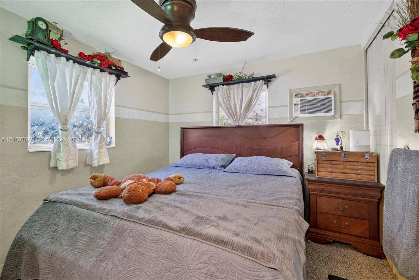 2864 NE 12th Terrace, Pompano Beach, FL 33064 Bedroom featuring dual windows, ceiling fan with integrated lighting, wall-mounted air conditioning unit, and sliding closet doors