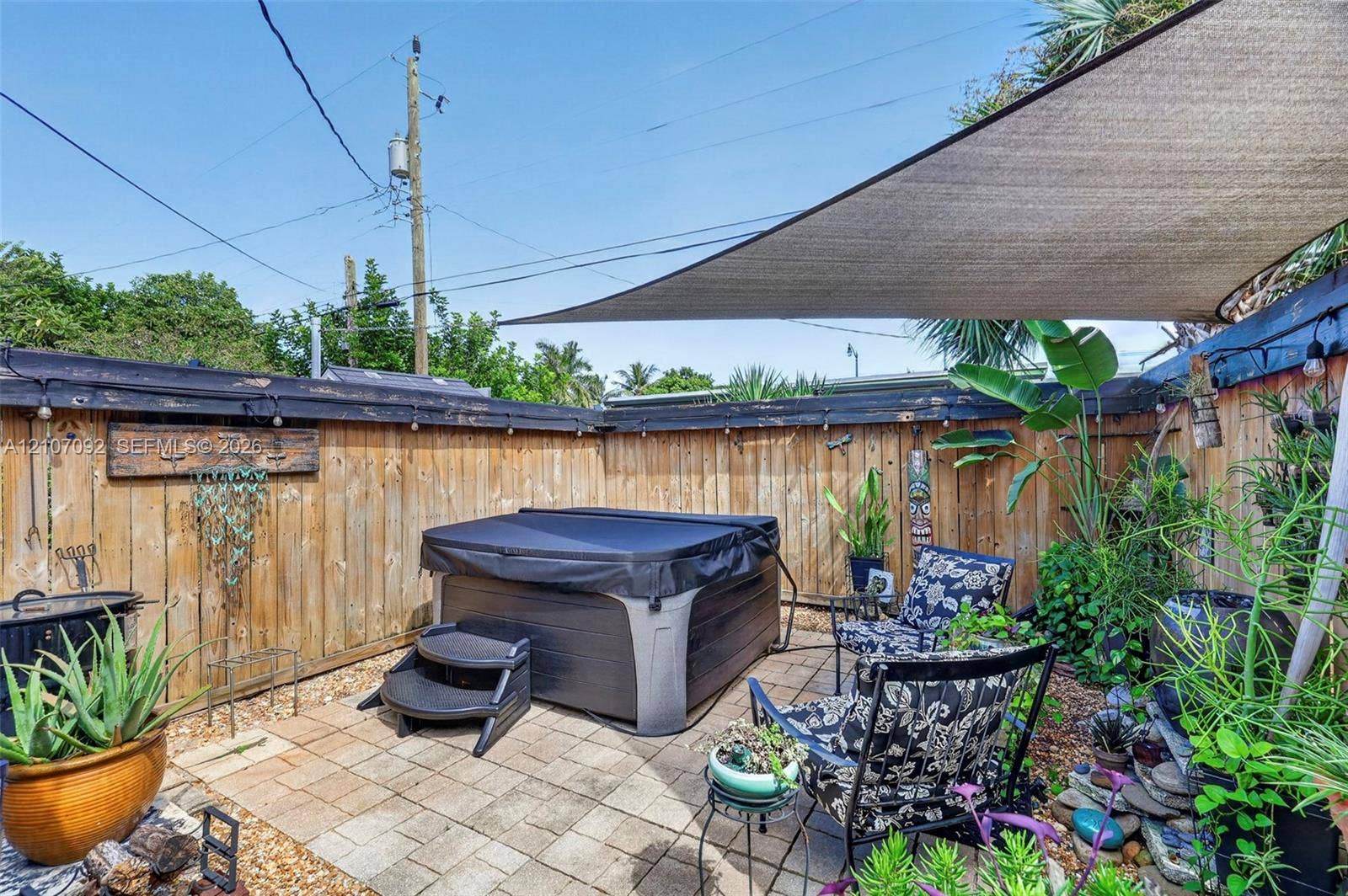 2864 NE 12th Terrace, Pompano Beach, FL 33064 Private outdoor space featuring hardscape stone pavers, a perimeter wood privacy fence, and an overhead shade sail