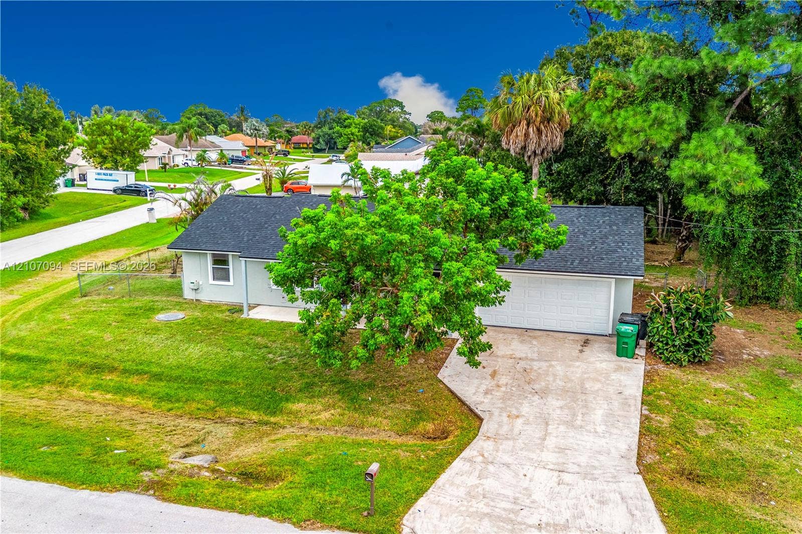 1131 SW London Lane, Port St Lucie, FL 34953 Single-story residence featuring a shingle roof, attached two-car garage, concrete driveway, and established landscaping