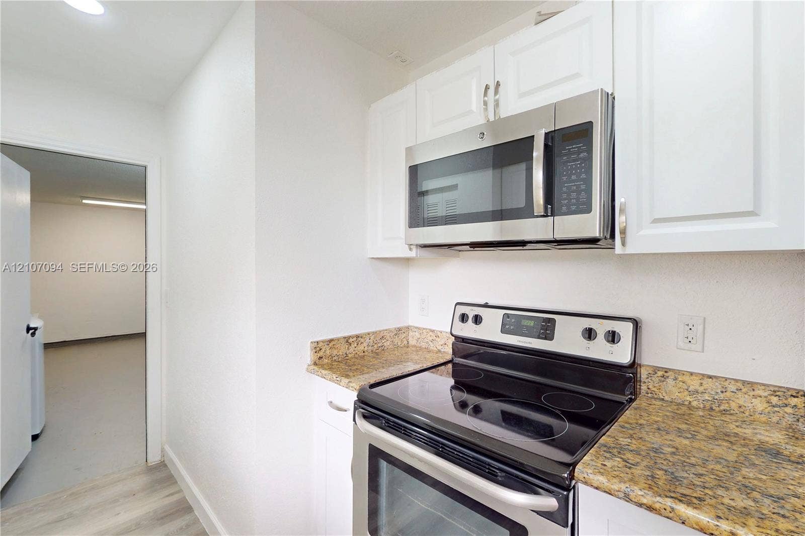 1131 SW London Lane, Port St Lucie, FL 34953 Kitchen featuring white cabinetry, stone-surface countertops, and stainless steel appliances including a built-in microwave and electric range