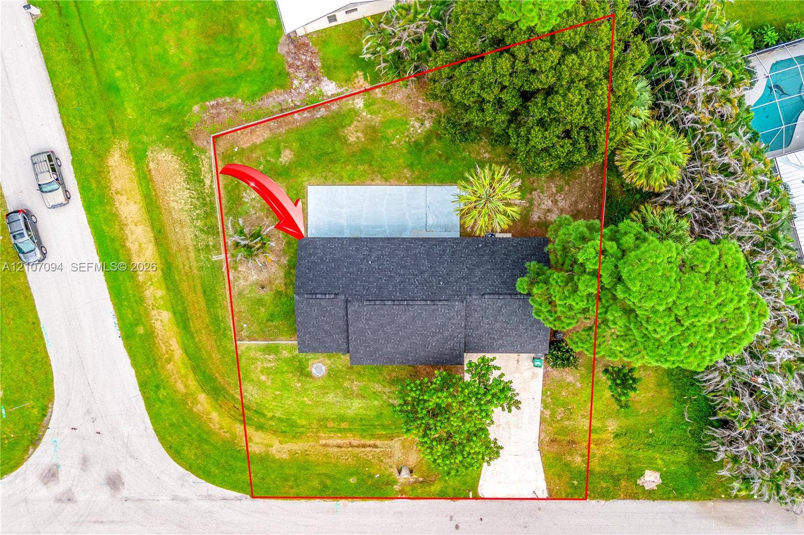 1131 SW London Lane, Port St Lucie, FL 34953 Aerial perspective of a property lot featuring mature landscaping, a paved driveway, and an expansive lawn