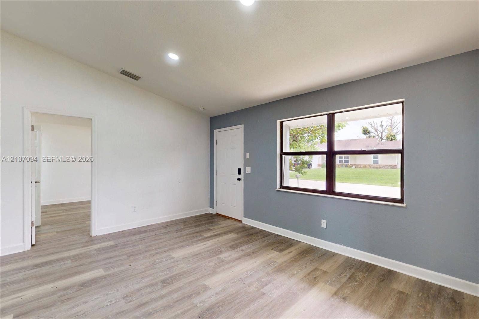 1131 SW London Lane, Port St Lucie, FL 34953 Vaulted ceilings, wood-finish flooring, recessed lighting, and a large picture window with dark-toned frames