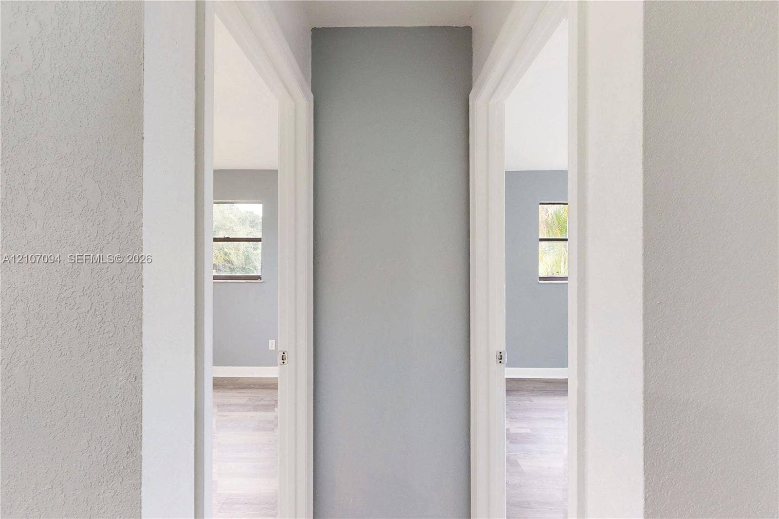 1131 SW London Lane, Port St Lucie, FL 34953 Interior hall featuring neutral-toned walls, wood-finish flooring, and two entryways with white door casings