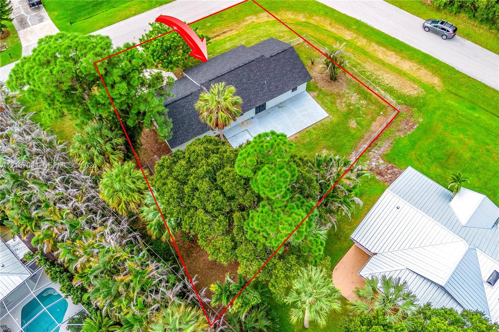 1131 SW London Lane, Port St Lucie, FL 34953 Aerial view of property featuring a shingle roof, concrete patio, expansive lawn, and mature canopy trees