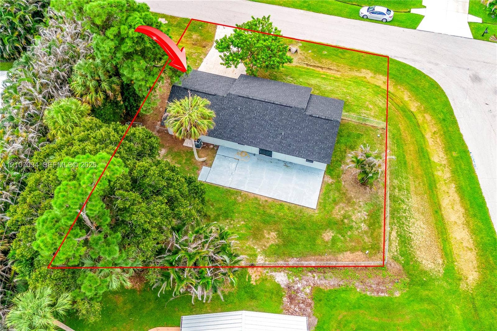 1131 SW London Lane, Port St Lucie, FL 34953 Aerial perspective of a property featuring a corner lot, a concrete patio, mature trees, and landscaping